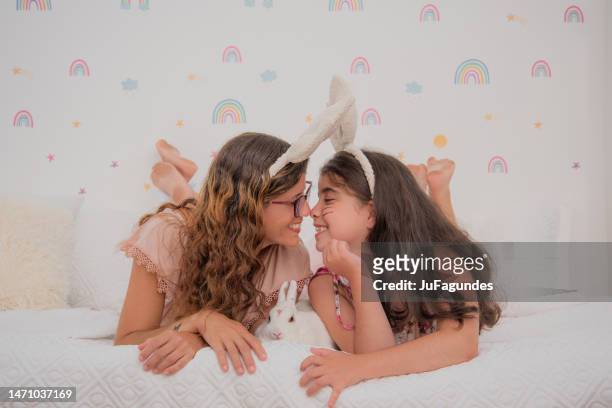 mother and daughter with bunny ears touching noses - nuzzling stockfoto's en -beelden