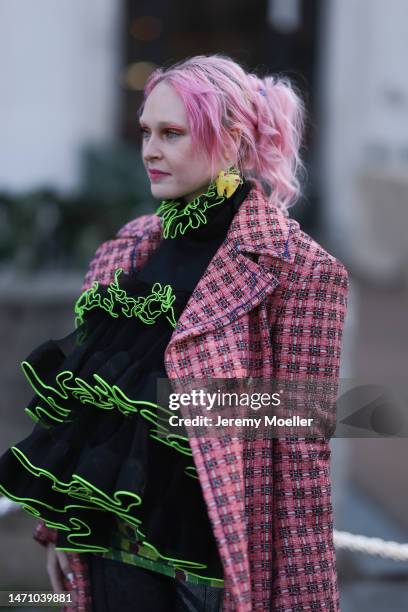 Fashion week guest seen wearing a pink patterned coat and a black and neon green puffer shirt before the Cecilie Bahnsen show on March 01, 2023 in...