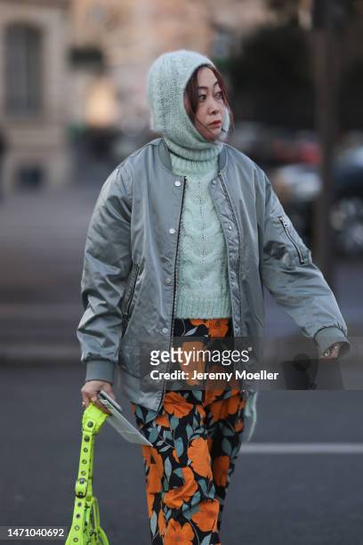 Fashion week guest seen wearing a neon green Balenciaga le cagole leather bag, a bomber jacket, a light blue knit balaclava, with a matching knit...