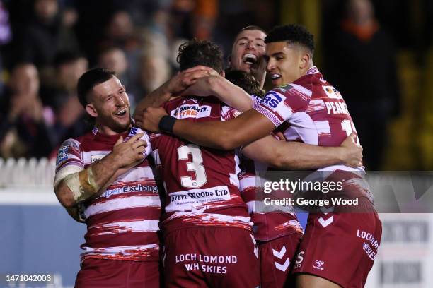 Toby King of Wigan Warriors celebrates with Cade Cust andteammates after scoring the team's fourth try during the Betfred Super League between...