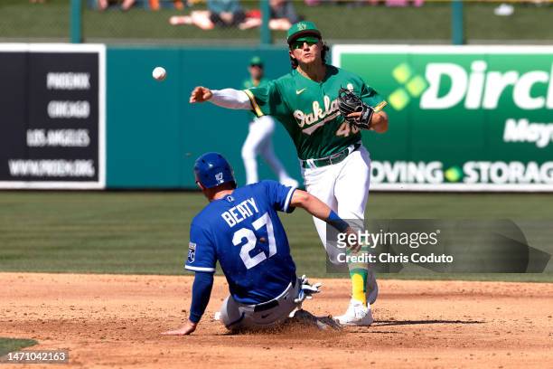Zack Gelof of the Oakland Athletics turns a double play over Matt Beaty of the Kansas City Royals during the third inning of a spring training game...