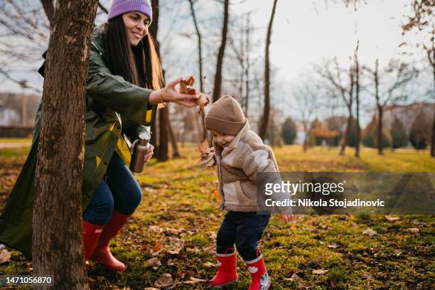 young mother and her son having fun in a public park - mother son shower stockfoto's en -beelden