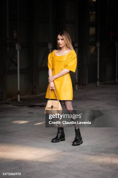 Emma Roberts wears a yellow leather mini dress, black boots and beige bag, outside Chloe, during Paris Fashion Week - Womenswear Fall Winter 2023...