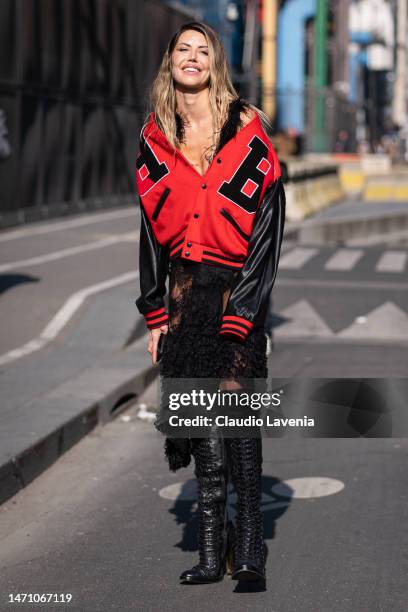 Guest wears a red and black jacket, lace black skirt and black boots, outside Chloe, during Paris Fashion Week - Womenswear Fall Winter 2023 2024, on...