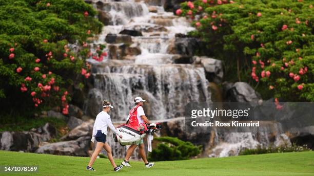 Nelly Korda of The United States and her caddie walk past the waterfall on the third hole during Day Three of the HSBC Women's World Championship at...