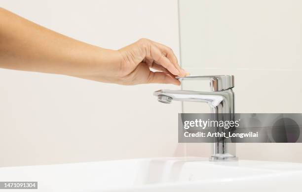 Woman push to close chrome faucet washbasin to washing hand soap for corona virus at water tap. push off water running drop off. Bathroom interior background with sink basin faucet tap.