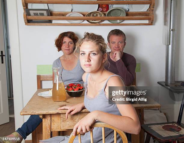 girl in kitchen, parents in background - mother daughter kitchen stock-fotos und bilder