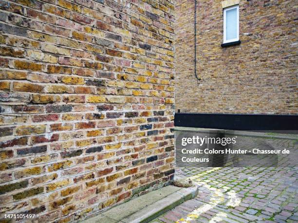 weathered brick walls on the corner of two cobbled streets in the paddington district (london, uk). - corners stock-fotos und bilder