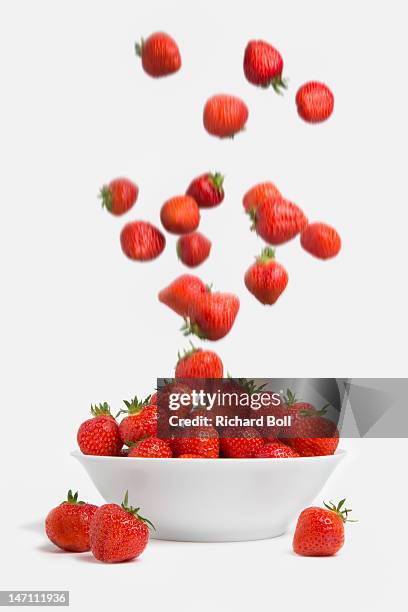 strawberries falling into a white bowl - strawberry falling stock-fotos und bilder