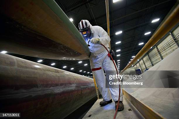 Employee Eric Callaway works on the exterior of a wind turbine blade made for General Electric Co.'s renewable energy business at TPI Composites...