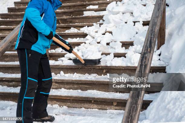 shoveling a snow from the stairs outside - blue winter tree stockfoto's en -beelden