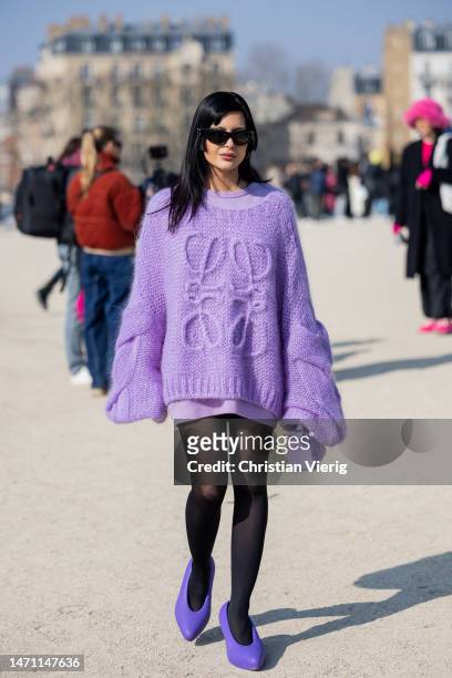 Maria Bernad wears lavender oversized knit with embroidered logo, tights, skirt, bag, heels outside Loewe during the Paris Fashion Week - Womenswear...