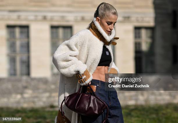 Caroline Daur is seen wearing a Loewe cream and tan faux fur coat, black top and blue Loewe jeans with maroon Loewe bag outside the Loewe show during...