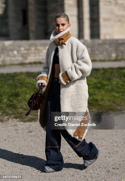 Caroline Daur is seen wearing a Loewe cream and tan faux fur coat, black top and blue Loewe jeans with maroon Loewe bag outside the Loewe show during...