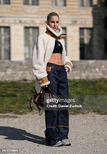Caroline Daur is seen wearing a Loewe cream and tan faux fur coat, black top and blue Loewe jeans with maroon Loewe bag outside the Loewe show during...
