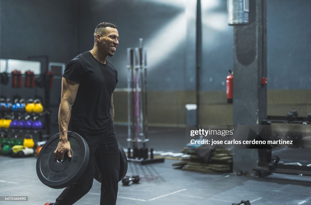 Hispanic strong man in gym picking up weights
