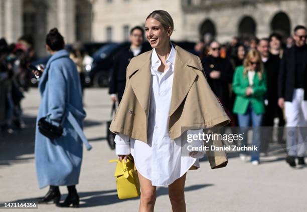 Leonie Hanne is seen wearing a Loewe tan jacket, white Loewe shirt dress, yellow Loewe bag outside the Loewe show during Paris Fashion Week F/W 2023...