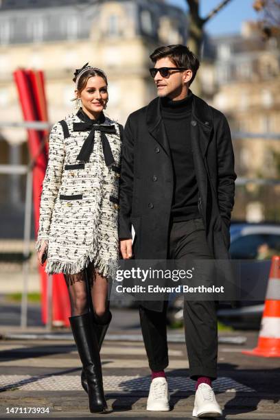 Olivia Palermo wears a black tulle knot hair clip, a pink velvet headband, diamonds and white pearls pendant earrings, a white with black embroidered...