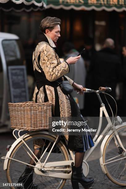 Fashion week guest seen wearing a black coat with snake pattern, black boots, black transparent tights and a black bag before the Chloe show on March...