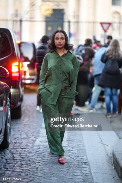 Paola Locatelli wears a gold chain necklace, a green shiny snake print pattern oversized silk shirt, matching green shiny snake print pattern...