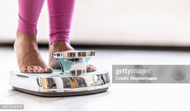 woman standing on scale; close-up of legs. - balancing scale stock pictures, royalty-free photos & images