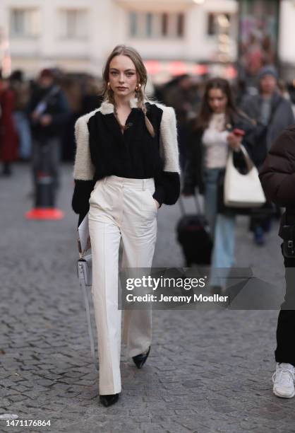 Fashion week guest seen wearing a black and white cardigan, beige pants, black heels and a light green bag before the Chloe show on March 02, 2023 in...