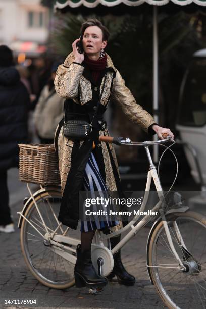 Fashion week guest seen wearing a black coat with snake pattern, black boots, black transparent tights and a black bag before the Chloe show on March...