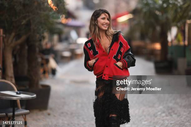Fashion week guest seen wearing a red and black college jacket, a transparent black skirt and black high boots before the Chloe show on March 02,...
