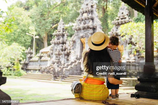 asian woman and her son visiting a pura, hinduism bali temple - bali stock pictures, royalty-free photos & images