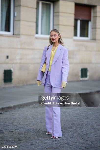 Victoria Magrath wears a pale yellow tulle shirt, a pale purple blazer jacket, matching pale purple flared suit pants, a pale yellow shiny leather...
