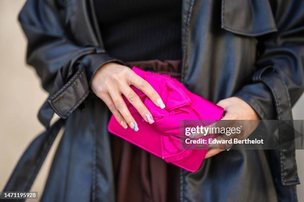 Samia Laaboudi wears a black turtleneck ribbed t-shirt from Courreges, a black shiny leather long coat, dark brown large suit pants, a neon pink...