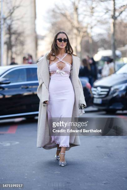 Tamara Kalinic wears black vintage sunglasses, a pale purple laces ruffled neck / cut-out chest / long silk dress, a beige gray wool long coat, a...