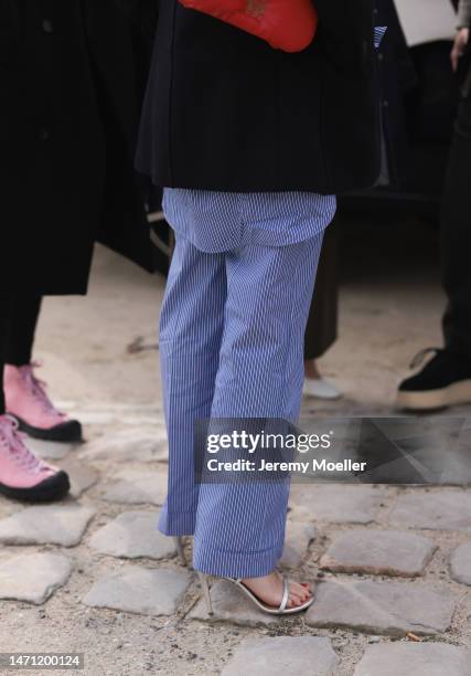 Fashion week guest seen wearing a total Loewe look with a blazer, a red bag and a white and blue striped blouse before the Loewe show on March 03,...