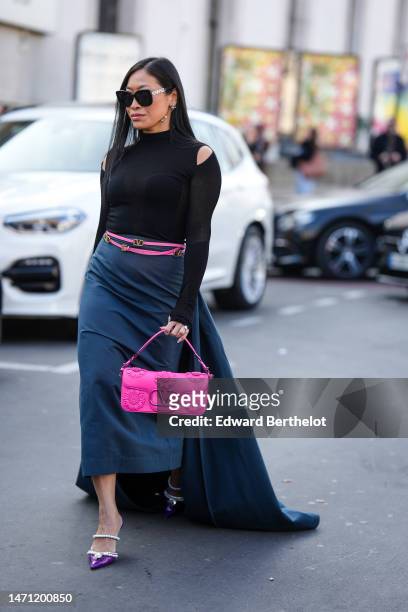 Miki Cheung wears black sunglasses from Chanel, silver and crystals logo pendant earrings from Chanel, a black high neck / cut-out shoulder / long...