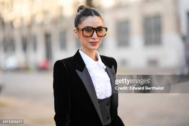 Heart Evangelista wears brown sunglasses, diamonds earrings, a white ruffled neck shirt, a black velvet blazer jacket, matching black velvet with a...