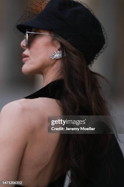 Marina Theodoridou seen wearing black hat Dior, black oversized jacket Alaia, black vest with gold buttons Schiaparelli, blue high waist jeans Rt13,...