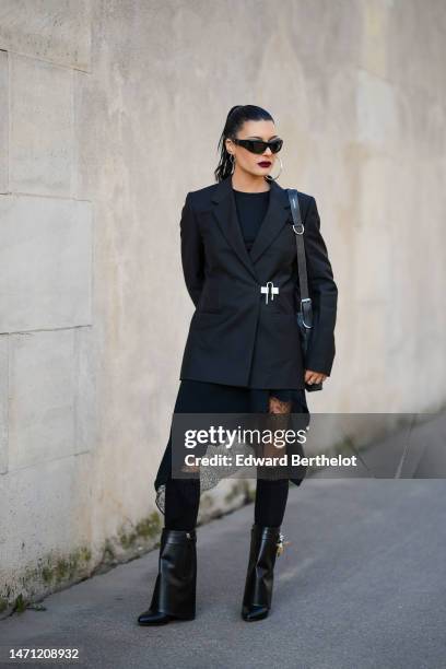 Maria Bernad wears black sunglasses, silver pendant earrings, a black t-shirt, a black asymmetric silk / embroidered lace pattern knees skirt, a...