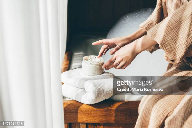 woman taking care of her skin. young woman in bathroom applying cream. - handschoen stock-fotos und bilder