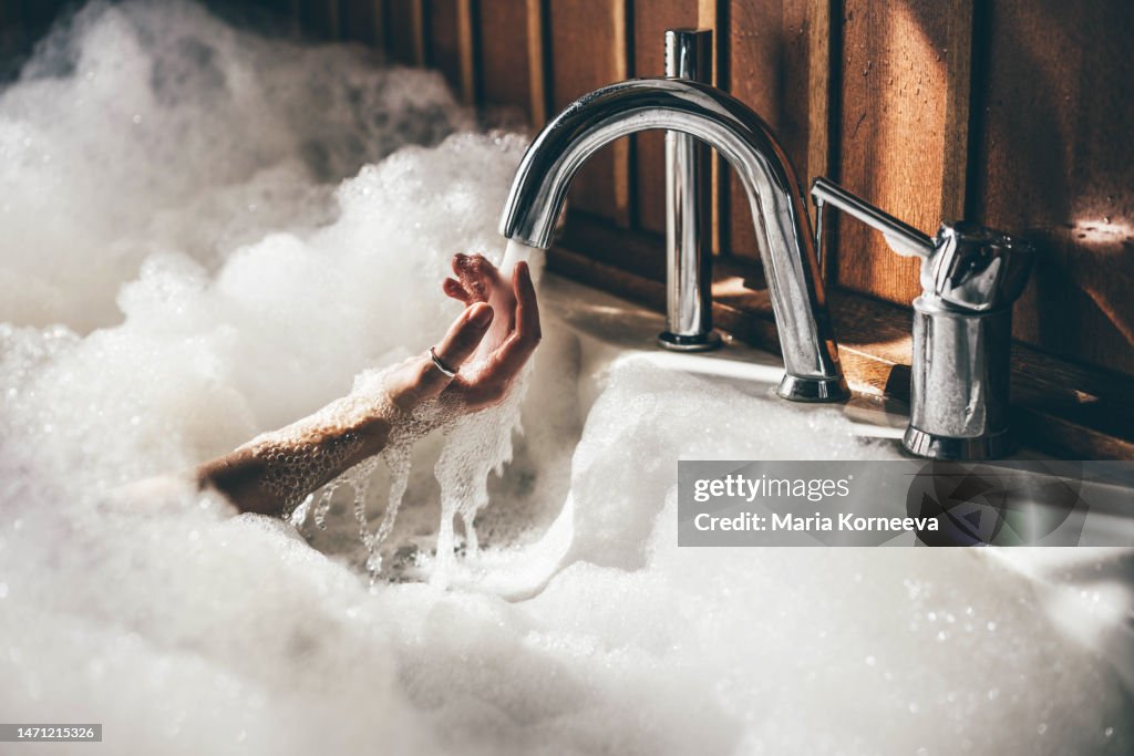 Woman holds her hands underwater in a bath.