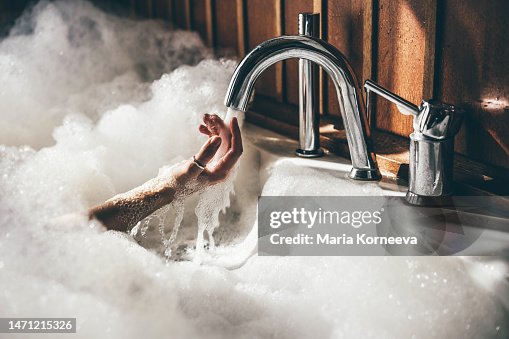 Woman holds her hands underwater in a bath.