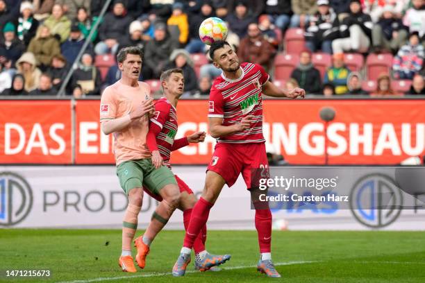 Maximilian Bauer of FC Augsberg heads the ball whilst under pressure from Jens Stage of SV Werder Bremen during the Bundesliga match between FC...