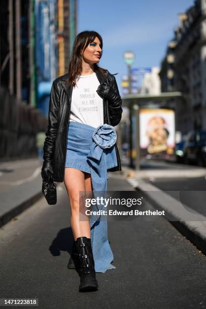 Carlotta Rubaltelli wears earrings, a white with gray inscription "We Should All Be Feminists" slogan print pattern t-shirt, a black shiny leather...