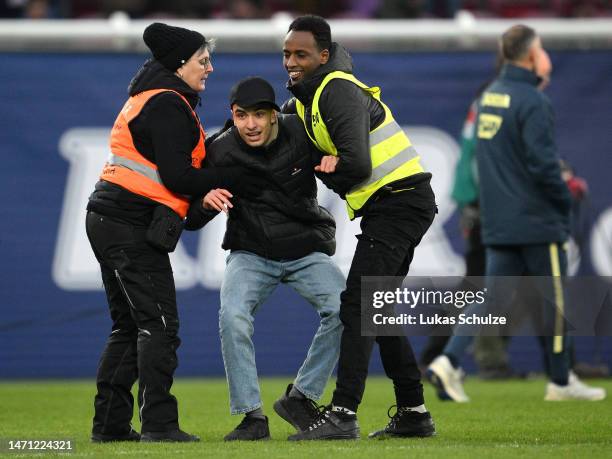 Streaker on the pitch is detained by security following the Bundesliga match between 1. FSV Mainz 05 and TSG Hoffenheim at MEWA Arena on March 04,...