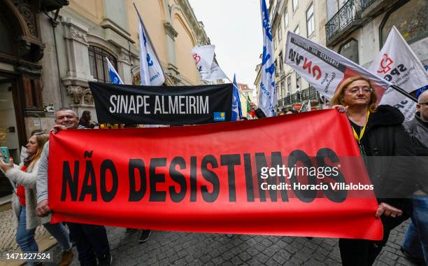 Teachers wave flags while marching behind banners from Rossio Square for better working conditions to the Portuguese Parliament during a strike...