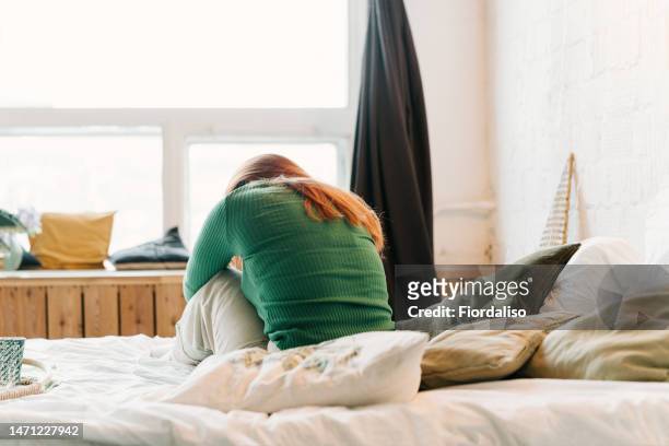 portrait of a red-haired woman sitting on the bed - femme visage caché photos et images de collection