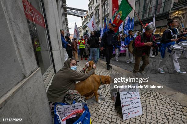 Deaf beggar holds her dogs as teachers wave flags while marching by for better working conditions from Rossio Square to the Portuguese Parliament...