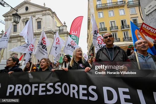 Teachers wave flags while marching behind banners from Rossio Square for better working conditions to the Portuguese Parliament during a strike...