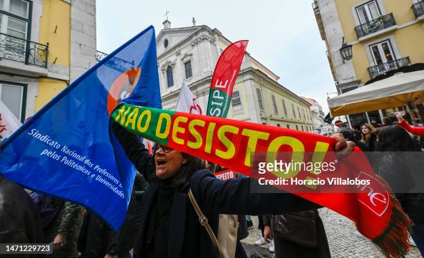 Teachers wave flags while marching behind banners in protest from Rossio Square for better working conditions to the Portuguese Parliament during a...