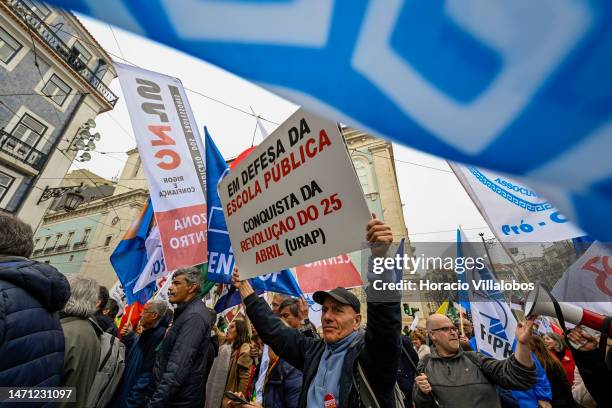 Teachers hold signs while marching in protest from Rossio Square for better working conditions to the Portuguese Parliament during a strike called by...