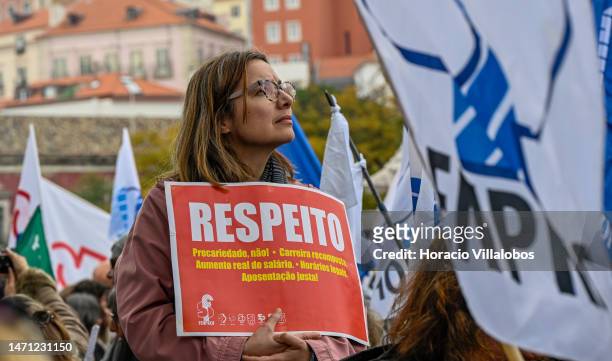 Teachers hold signs while marching in protest from Rossio Square for better working conditions to the Portuguese Parliament during a strike called by...